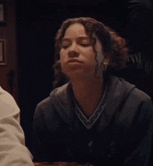 a woman with curly hair is wearing a grey sweater with a v-neck