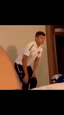 a man in a white shirt and black pants is standing in a room .