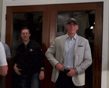 a man wearing a denver broncos hat stands in front of a glass door