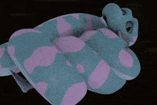 a stuffed animal with blue and pink spots is laying on a table