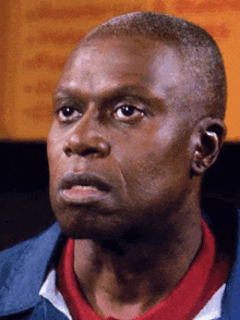 a close up of a man 's face with a blue jacket and a red shirt
