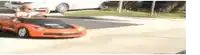 a little boy is driving a red toy car on a street