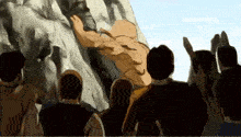 a group of people watching a man climb up a rock