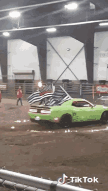 a green dodge challenger is driving down a dirt track
