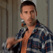 a man in a plaid shirt is making a funny face and pointing .