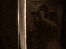 a woman in a white dress is standing in a doorway looking out a window