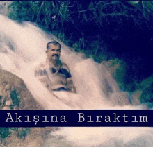 a man is sitting in the middle of a waterfall with a caption in a foreign language .