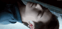 a close up of a person 's face with their eyes closed and a blue shirt on .