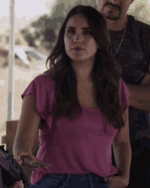 a woman in a pink shirt has a necklace with the letter c on it