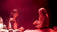two women are playing with stuffed animals in a red light