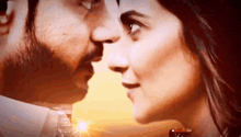 a man and a woman are kissing each other in front of a sunset .