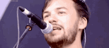a man with a beard singing into a microphone .