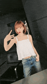 a woman in a white tank top and jeans takes a selfie in front of a mirror