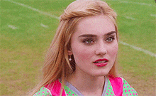 a close up of a woman 's face while standing on a football field .