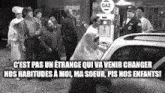 a group of men are standing around a car in front of a gas pump .