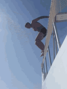 a man is jumping over a fence into a body of water