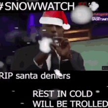 a man wearing a santa hat is talking into a microphone with the caption #snowwatch rip santa denters rest in cold will be trolled