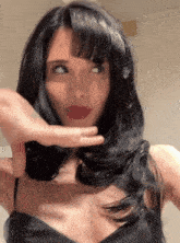 a woman with long black hair and red lipstick is making a funny face
