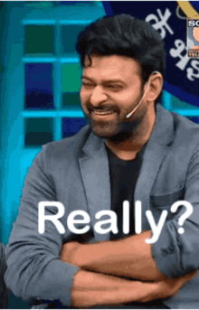 a man with a microphone on his ear is smiling and says " really "