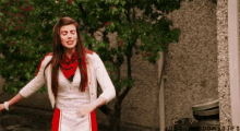 a woman in a red and white dress is dancing in front of a tree ..