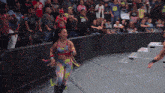 a woman in a colorful outfit with the number 14 on her shirt stands in front of a crowd of people
