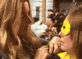 a woman with a yellow mask on her face looks at another woman