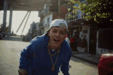 a young man wearing a blue sweatshirt and a white hat with the letter n on it