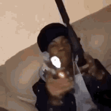 a man is holding a gun in his hand while sitting on a couch .