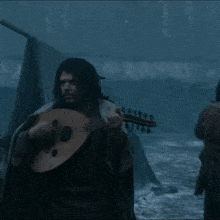 a man is playing a guitar while another man plays a drum