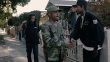 a man in a panthers jacket shakes hands with a man in a camouflage jacket