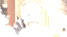 a man with glasses and a beard is smiling in front of a sign that says ' o ' on it