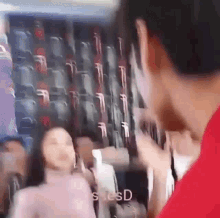 a man in a red shirt is talking to a woman in a pink dress in front of a wall of seats .