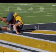 a man in a yellow and blue uniform is kneeling on a track