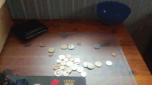 a bunch of coins on a wooden table with a wallet