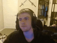 a man wearing headphones is sitting in front of a closet with swords on it