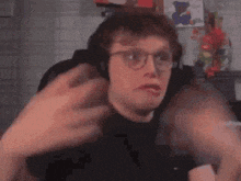 a man wearing glasses and headphones is making a funny face while sitting at a table .