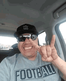 a man wearing a hat and sunglasses is giving the middle finger