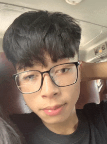 a young man wearing glasses is looking at the camera
