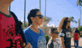 a woman wearing sunglasses and a blue shirt that says fiesta