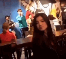 a woman is sitting at a table in front of a group of people in a room .