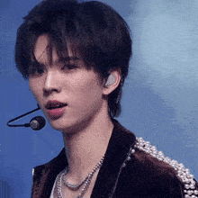 a young man wearing a jacket with pearls and a microphone