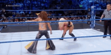 two women are wrestling in a ring with a referee watching .