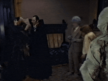 a group of people are standing in a dark room and one of them is wearing a hood