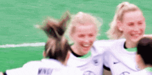 a group of female soccer players are hugging each other on a field and smiling .