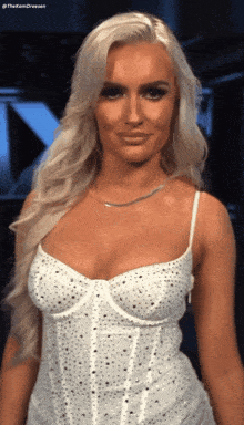 a woman wearing a white dress with rhinestones on it is smiling