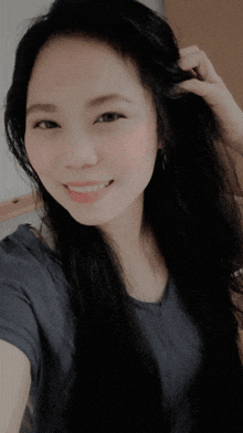 a woman in a blue shirt is smiling and holding her hair