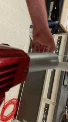 a person is using a red vacuum cleaner to remove a piece of duct tape