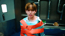 a young man is wrapped in orange tape while looking at something