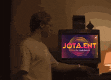 a man stands in front of a screen that says " jota ent "