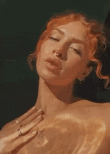 a woman with red hair is wearing a necklace and rings